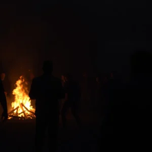 Fraternity party ambiance with a focus on shadows and an illuminative bonfire, representing the danger associated with hazing.